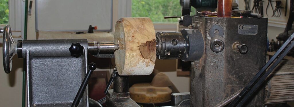 Wood mounted on a lathe in workshop.