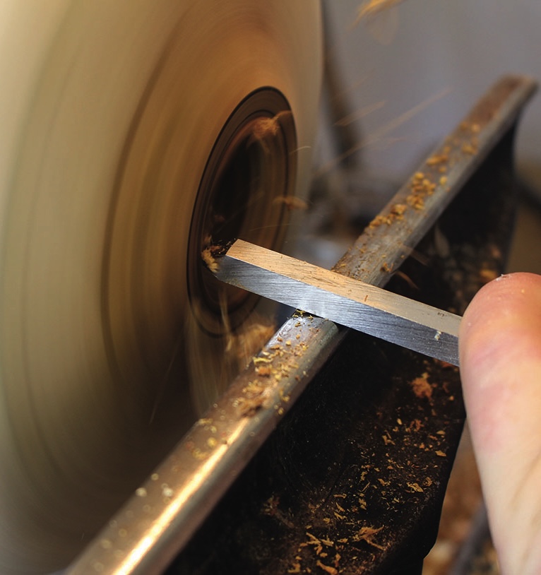 Woodturning with chisel on lathe.