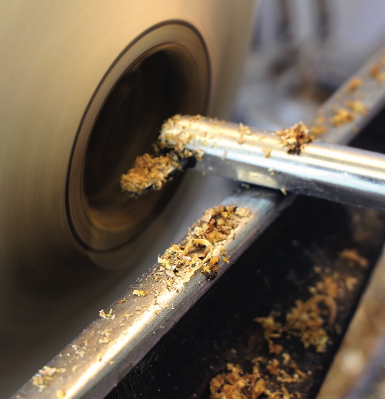 Woodturning lathe with wood shavings and tool.
