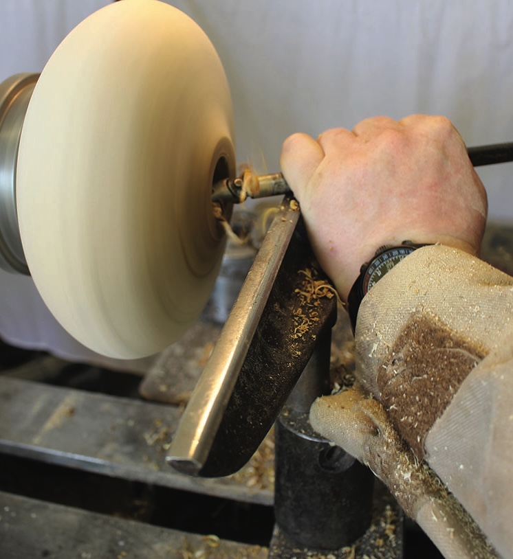Person woodturning on a lathe machine.