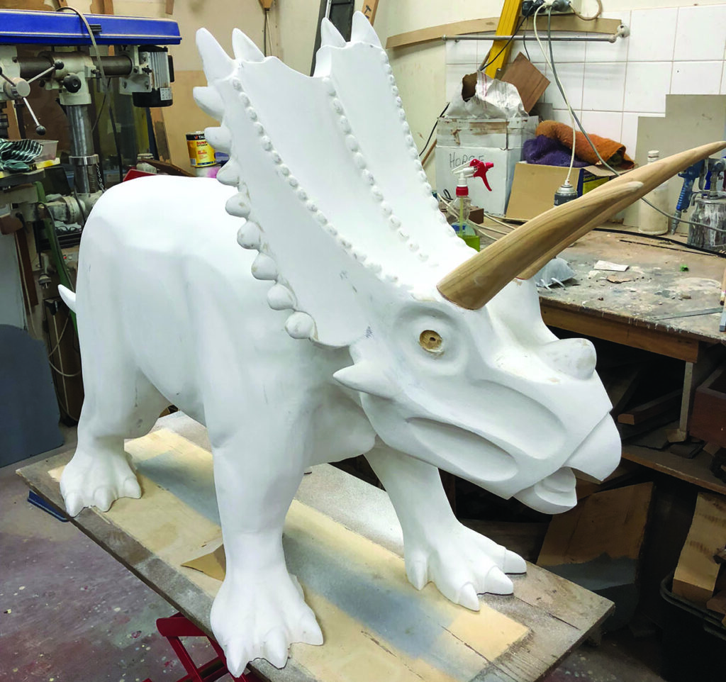 White triceratops sculpture in workshop with tools