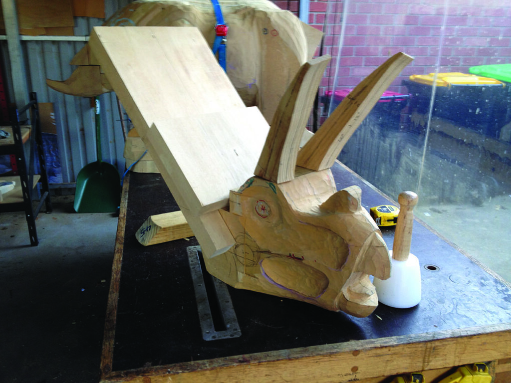 Wooden dinosaur sculpture in workshop.