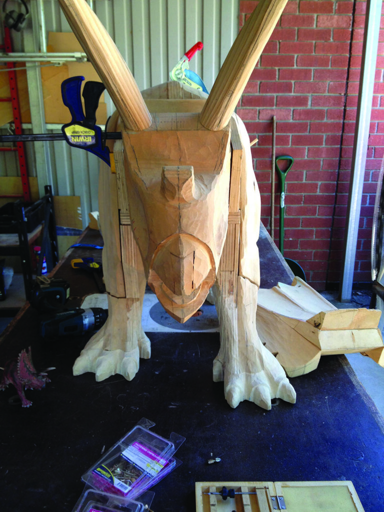 Wooden dinosaur model with clamps and tools.