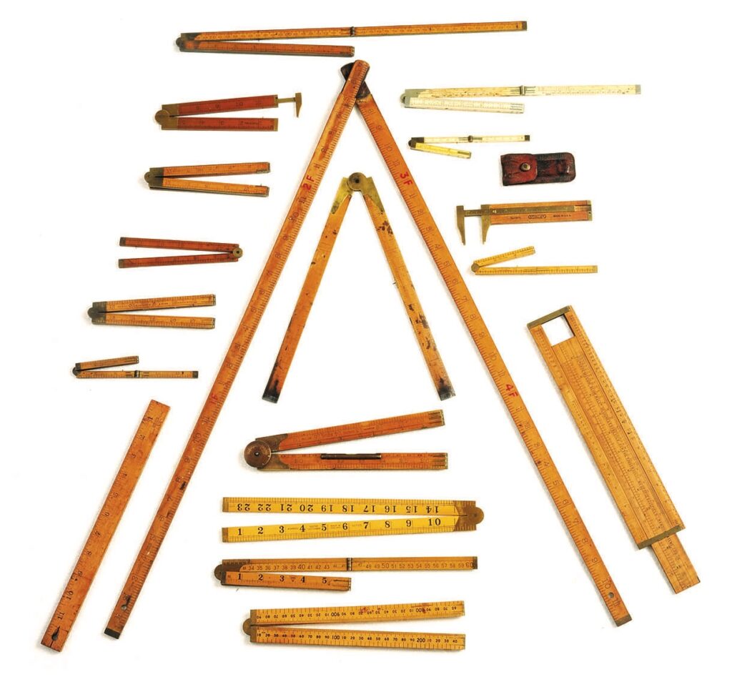 Collection of vintage folding rulers on display.