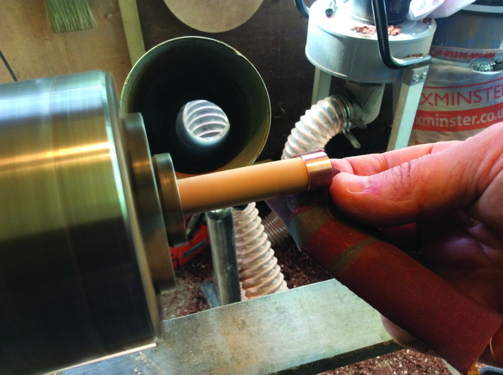 Person sanding wood on a lathe
