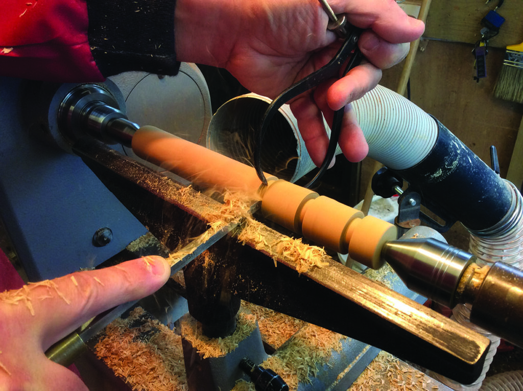Person woodturning on a lathe, creating shavings.