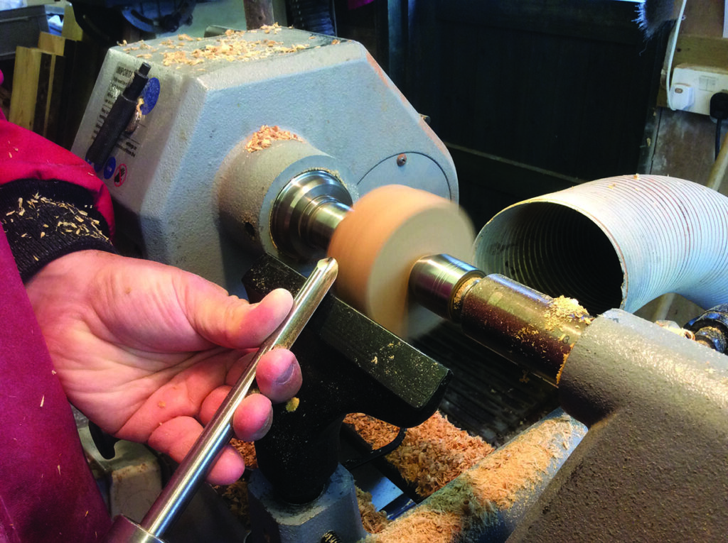 Woodturning on a lathe machine in workshop.