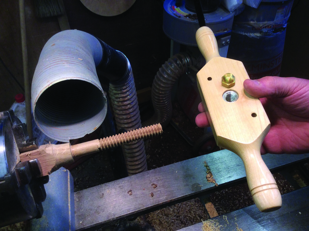 Wood lathe with wooden thread tool in workshop.