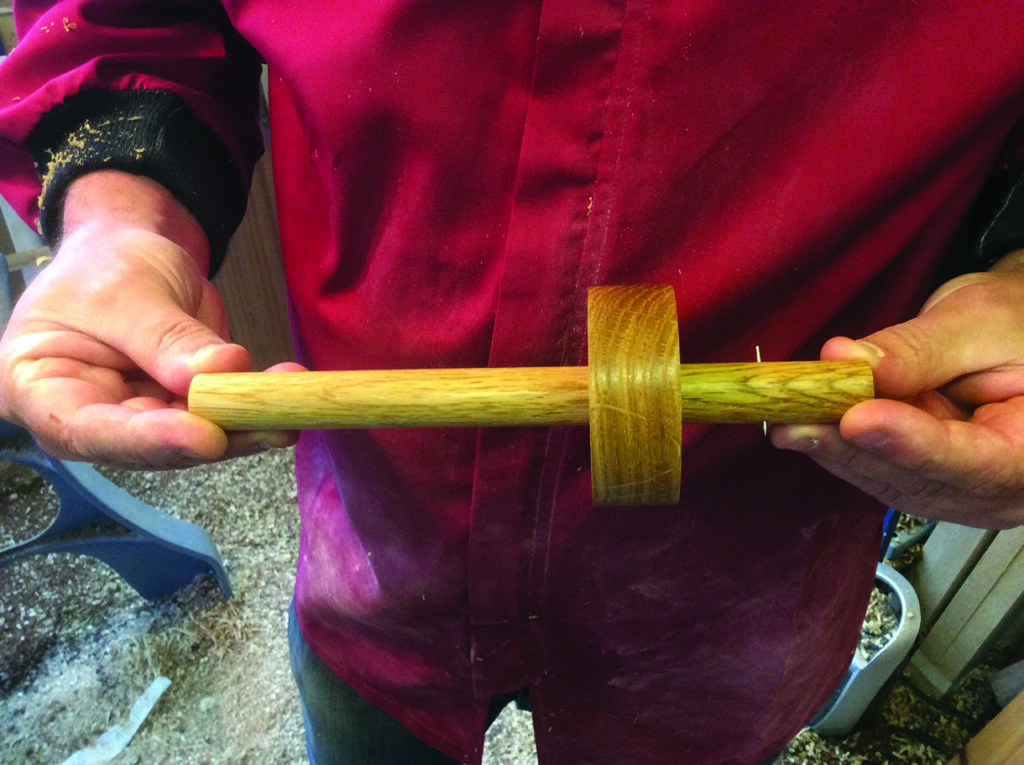 Person holding crafted wooden tool in workshop
