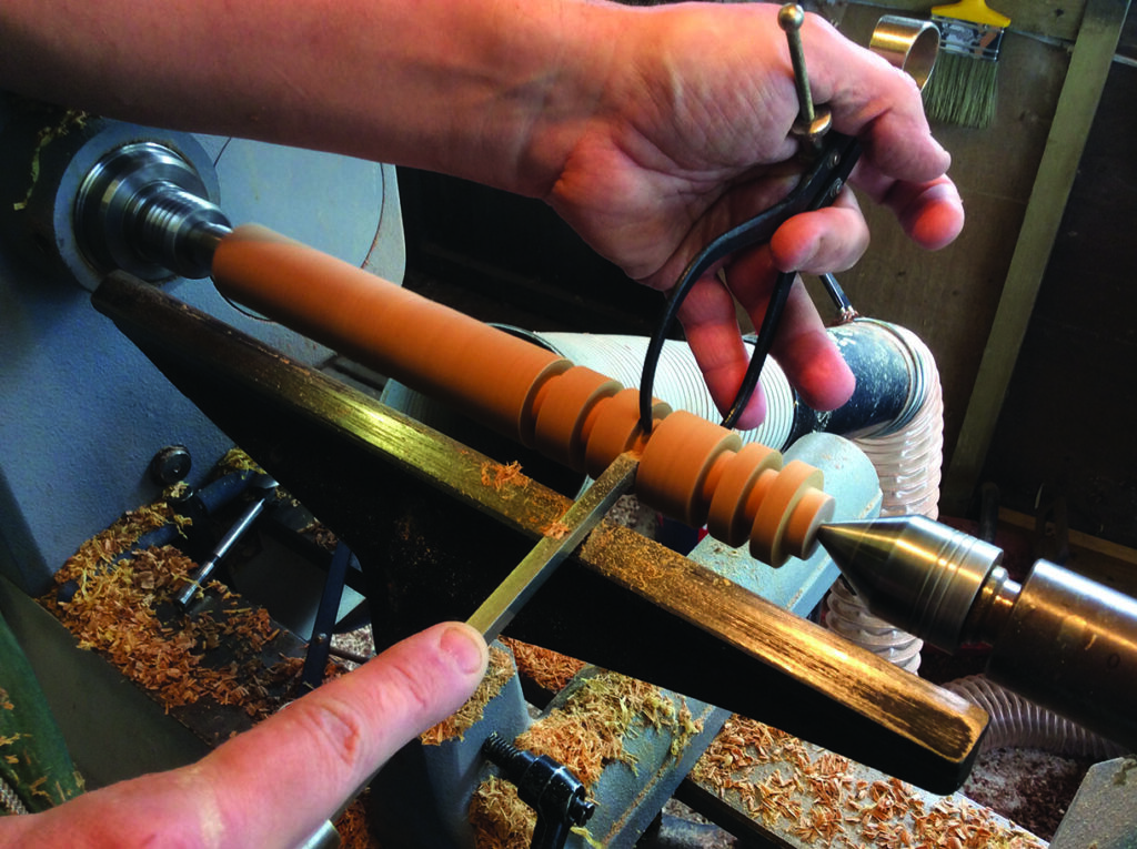 Woodturning on a lathe using calipers.