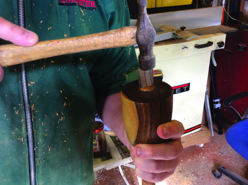 Person chiseling wood with a hammer.