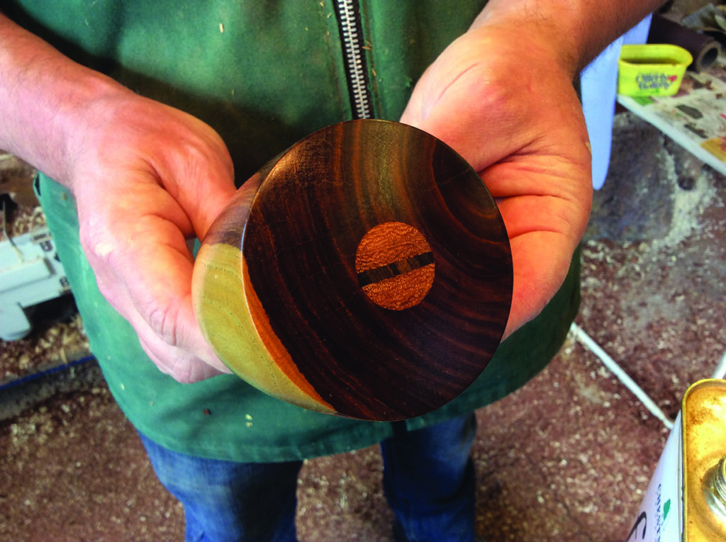 Person holding an intricate wooden cylinder