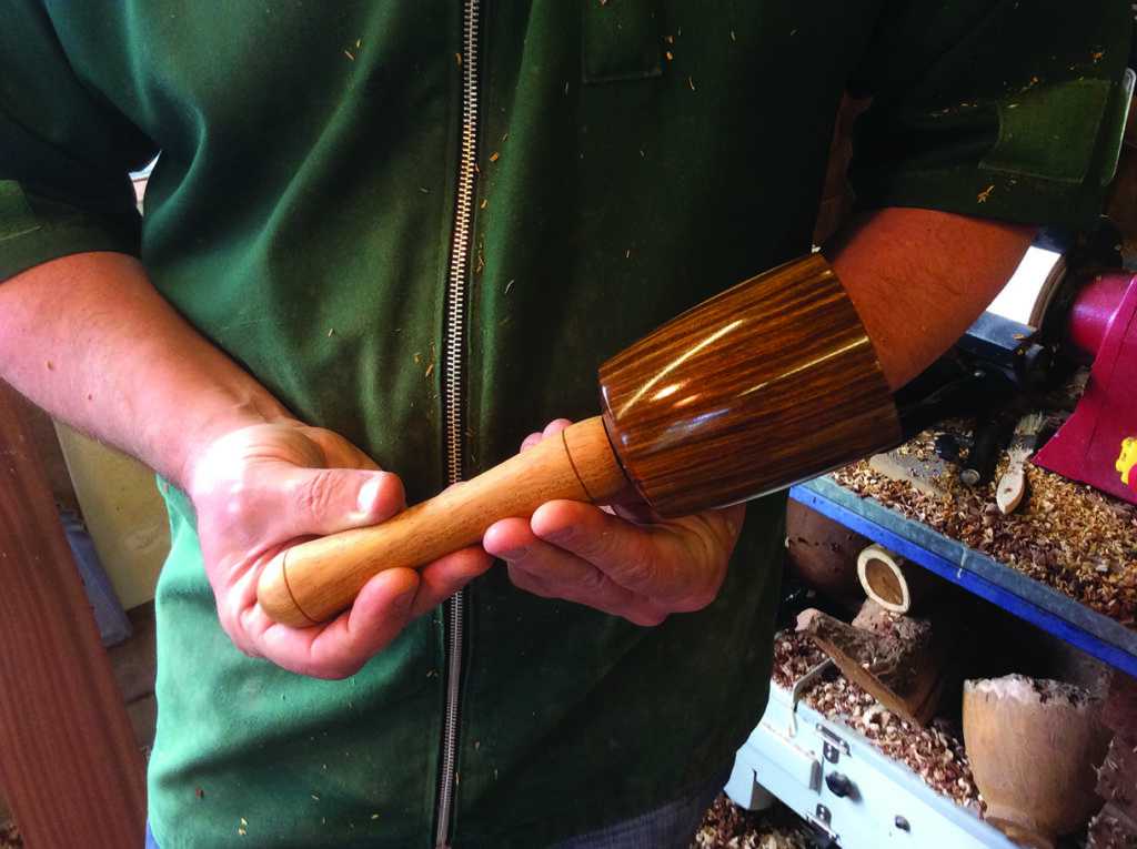 Craftsman holding a wooden mallet in workshop.