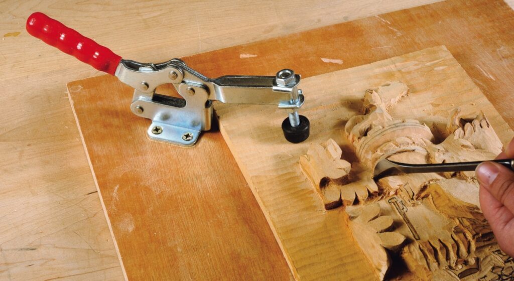 Wood carving secured with clamp, hand chiselling details.