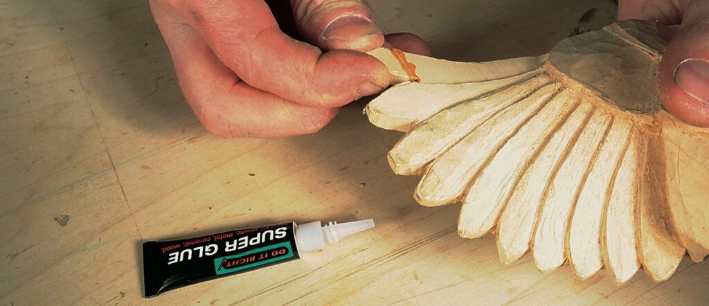 Gluing wooden sculpture with super glue tube nearby.