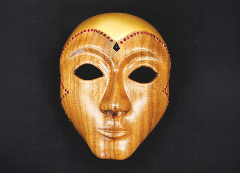 Decorative wooden mask with red accents on black background.