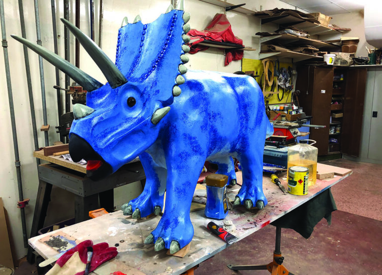 Blue triceratops sculpture in a workshop setting.