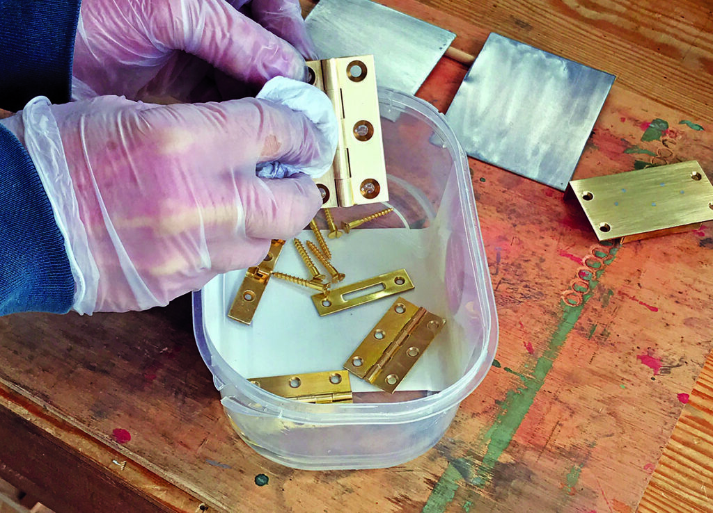 Person polishing brass hinges and screws.