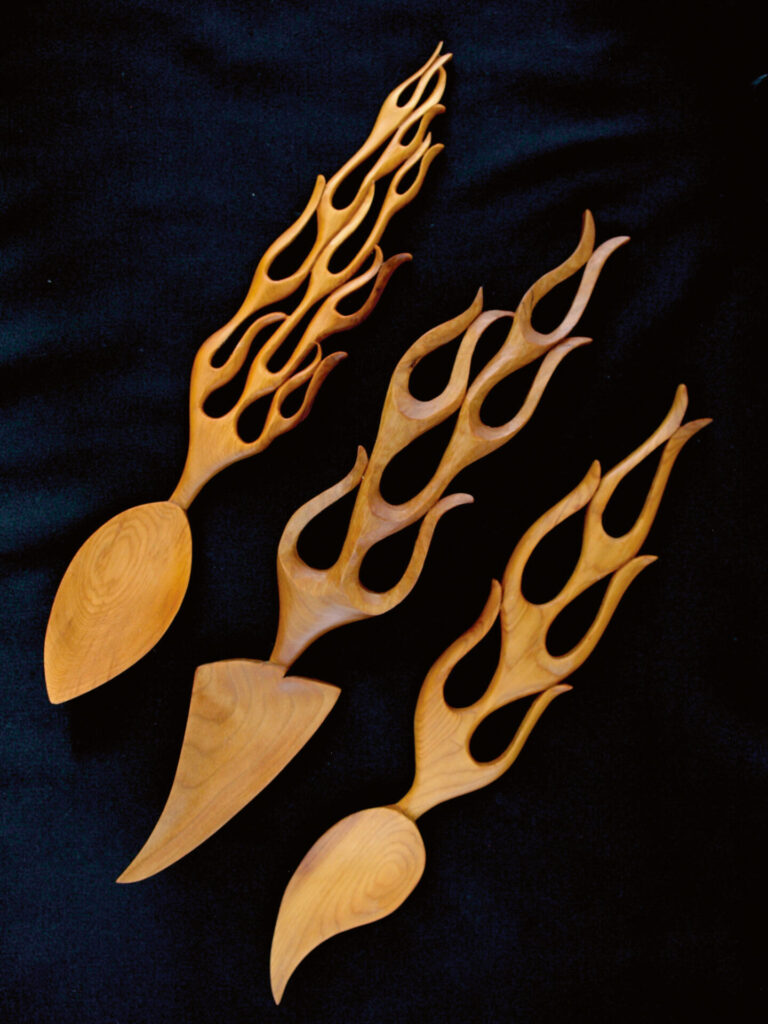 Wooden spoons with flame-like handles on black background.