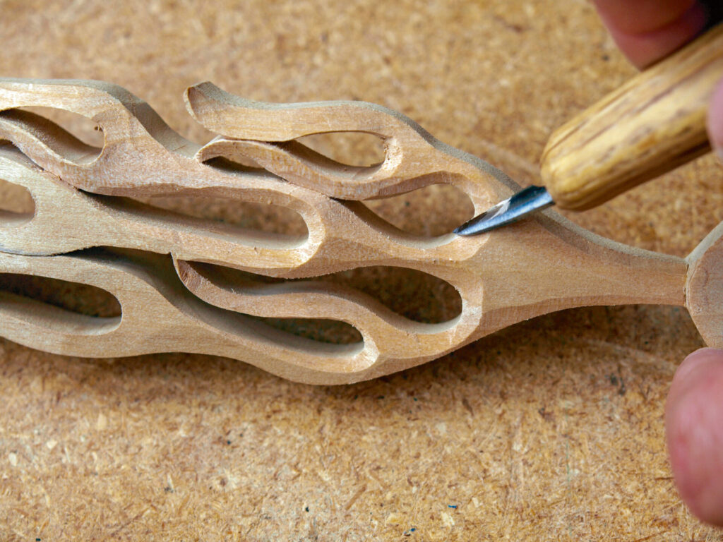 Hand carving intricate wooden spoon design.