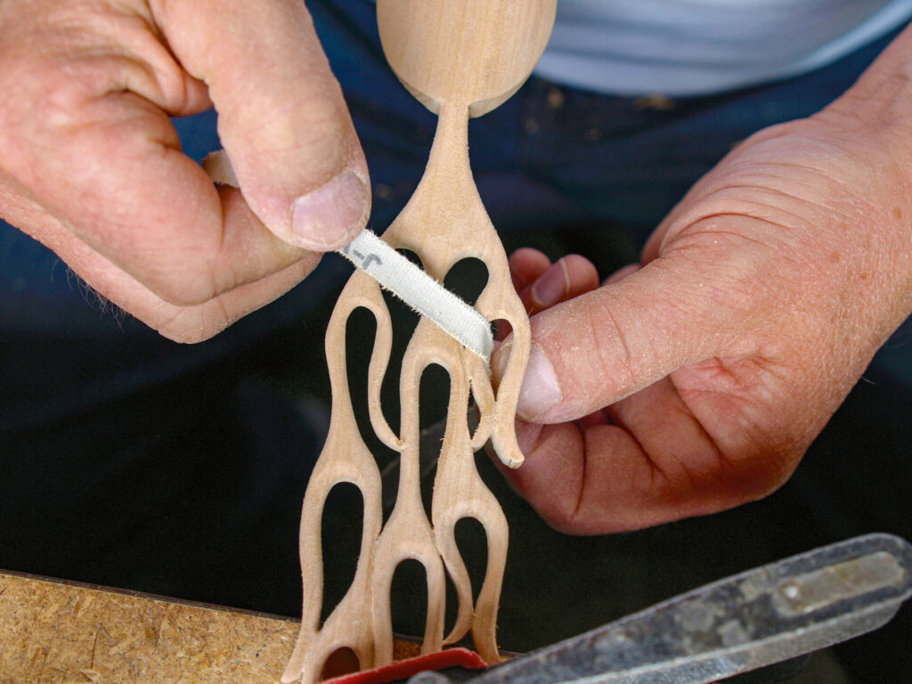 Hands carving intricate wooden sculpture details.