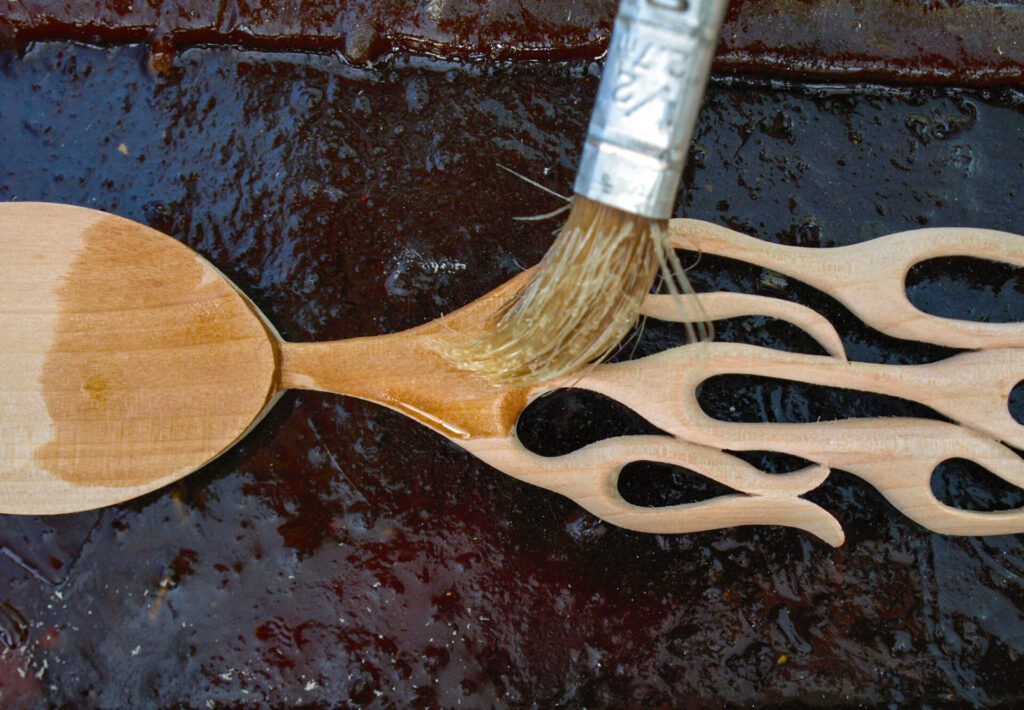 Brushing oil on artistic wooden spoon.