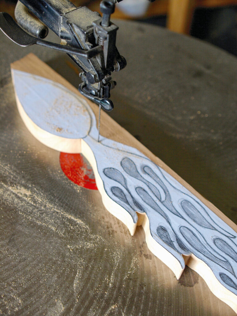 Scroll saw cutting ornate wooden pattern.