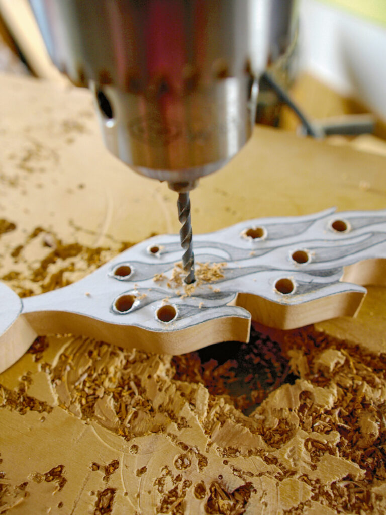 Drill cutting intricate wooden guitar headstock design.