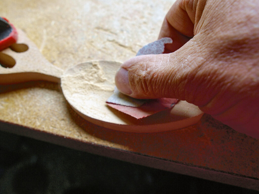 Person sanding wooden spoon by hand.