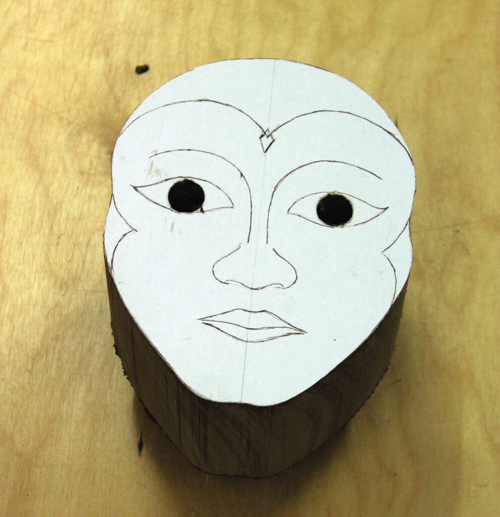 Wood carving face template on block of wood.