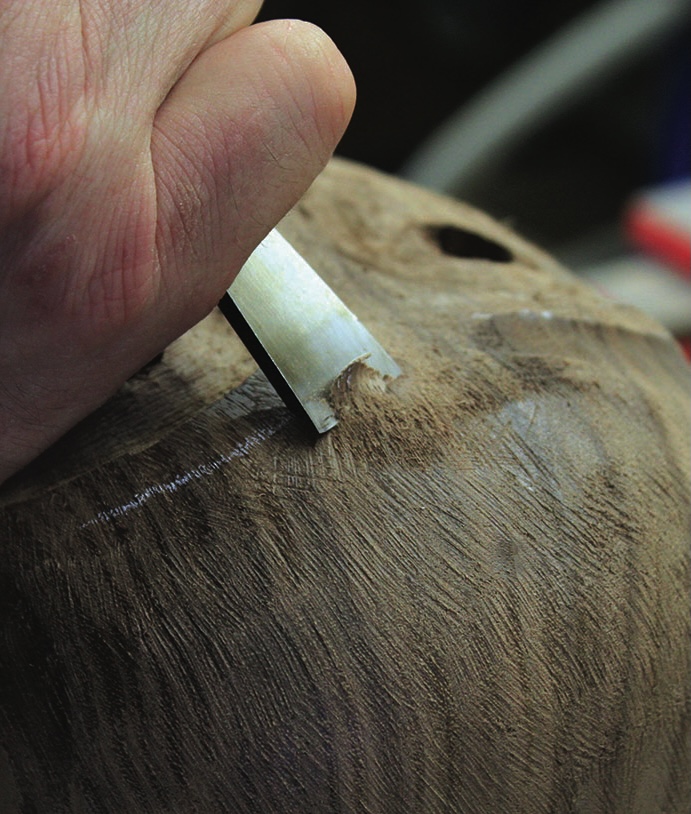 Person carving detailed wood sculpture by hand.