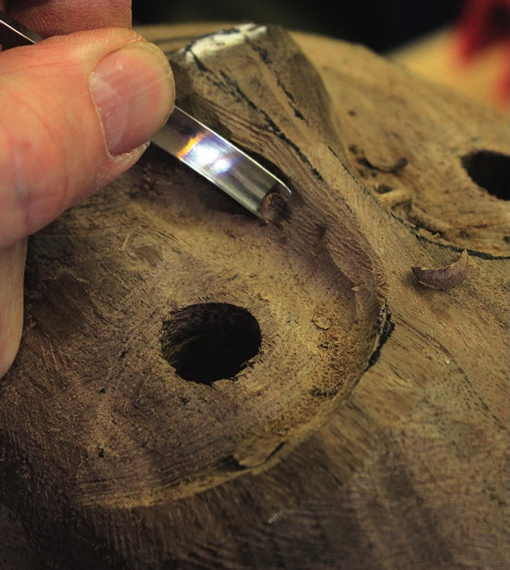 Craftsman carving wood sculpture with chisel.