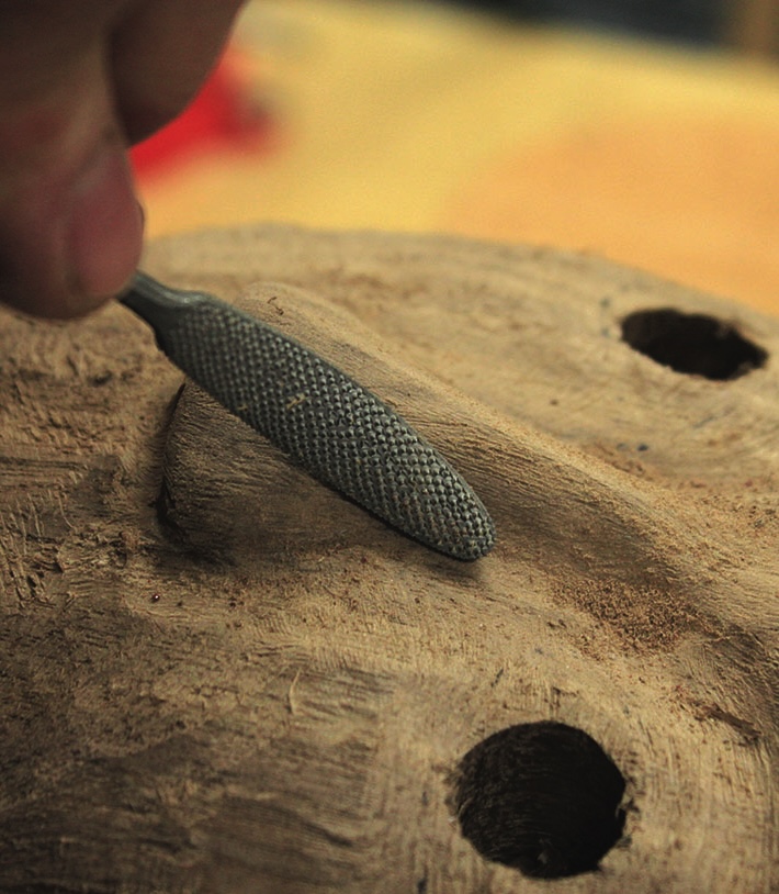 Hand carving wood with a metal file.