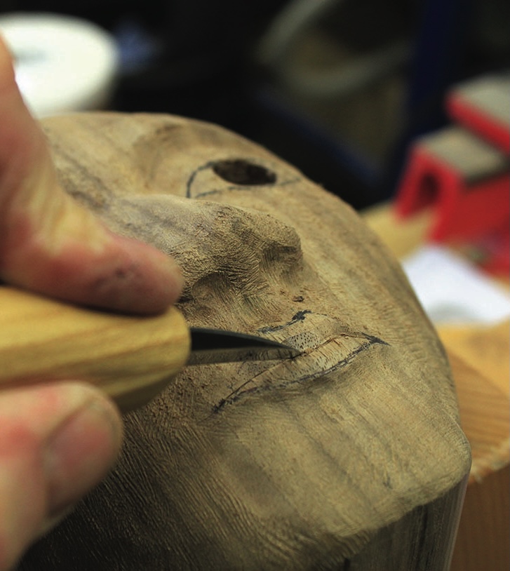 Hand carving lips on wooden sculpture.