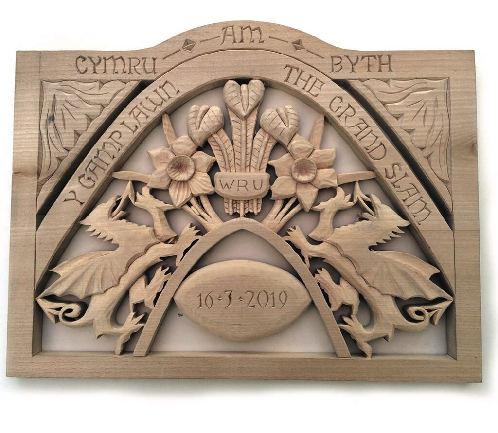 Welsh rugby wooden carving with dragons and flowers.