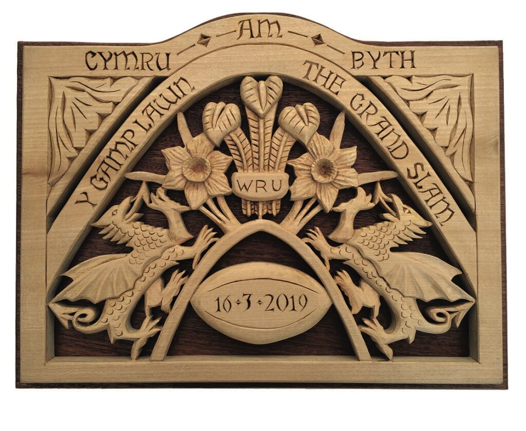 Welsh rugby wood carving with dragons and flowers.