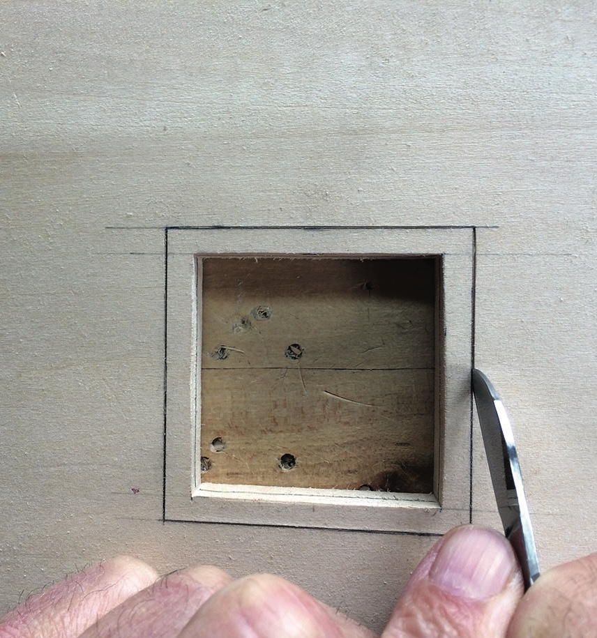 Hand chiseling square hole in wood.