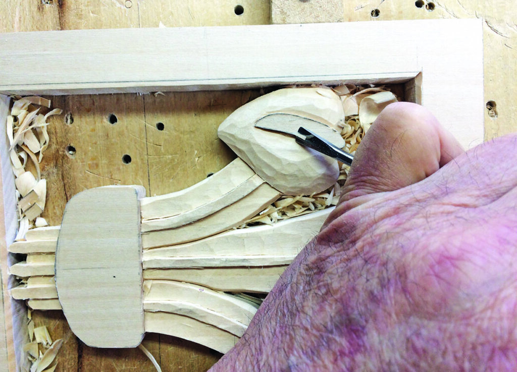 Hand carving intricate wooden sculpture with chisel