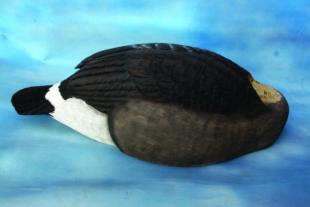 Carved wooden duck decoy on blue background.