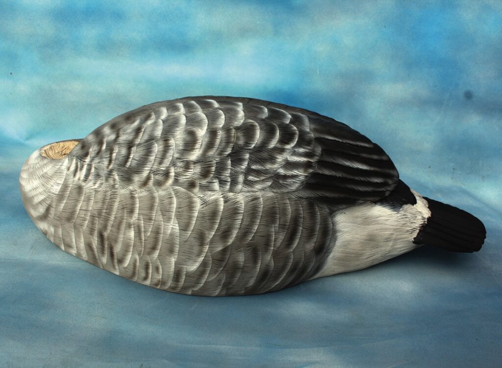 Realistic painted goose decoy on blue background.
