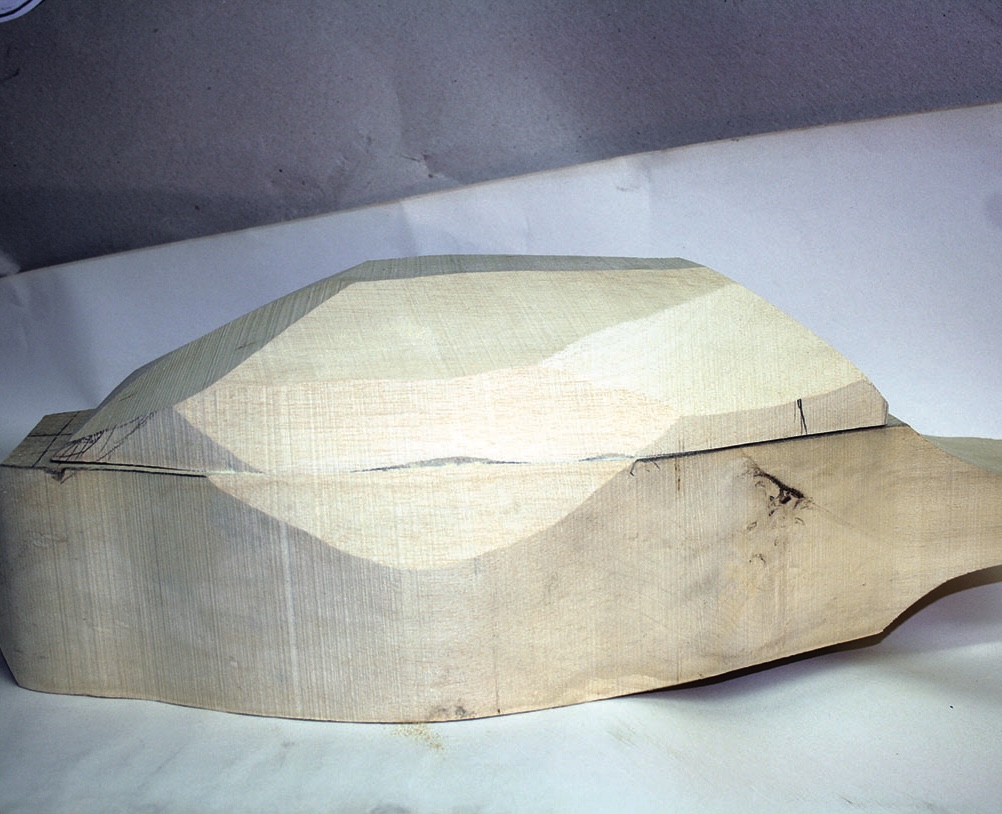 Unfinished wood carving on a tabletop surface.