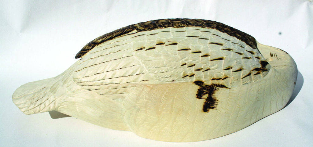 Wooden sculpted bird with intricate feather patterns.