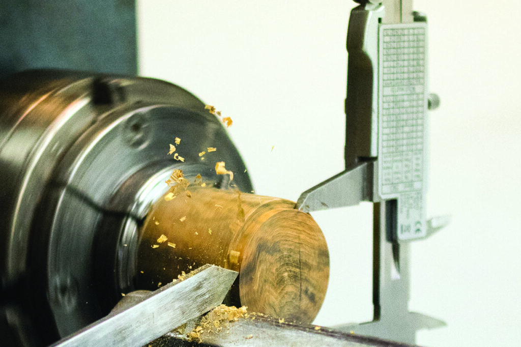 Woodturning with chisel and lathe shaving wood.
