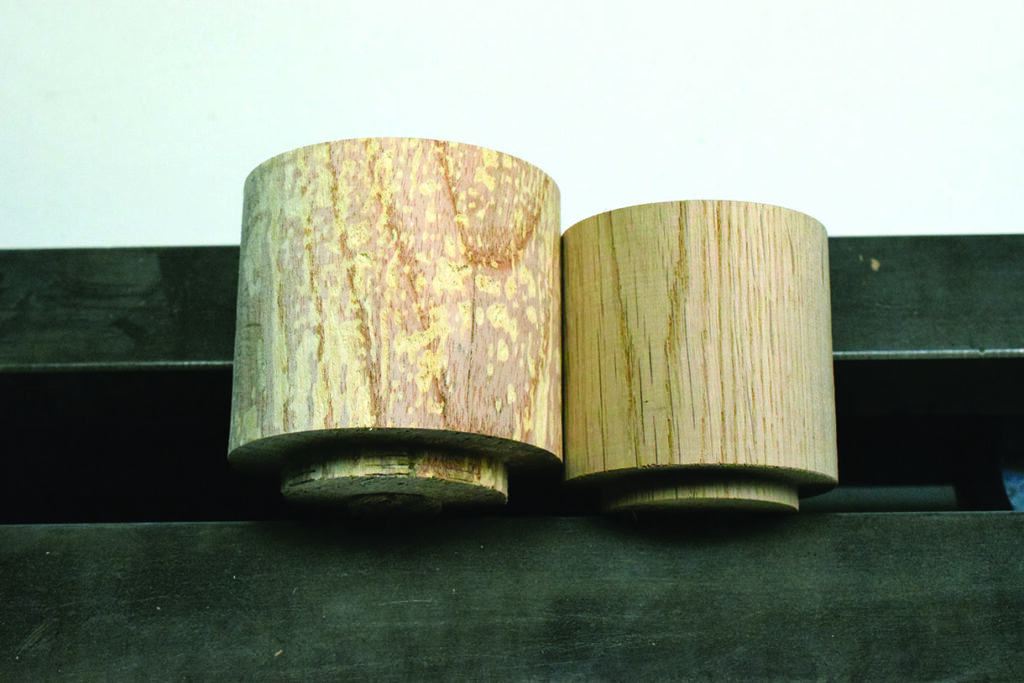 Two cylindrical wood blocks on black surface.