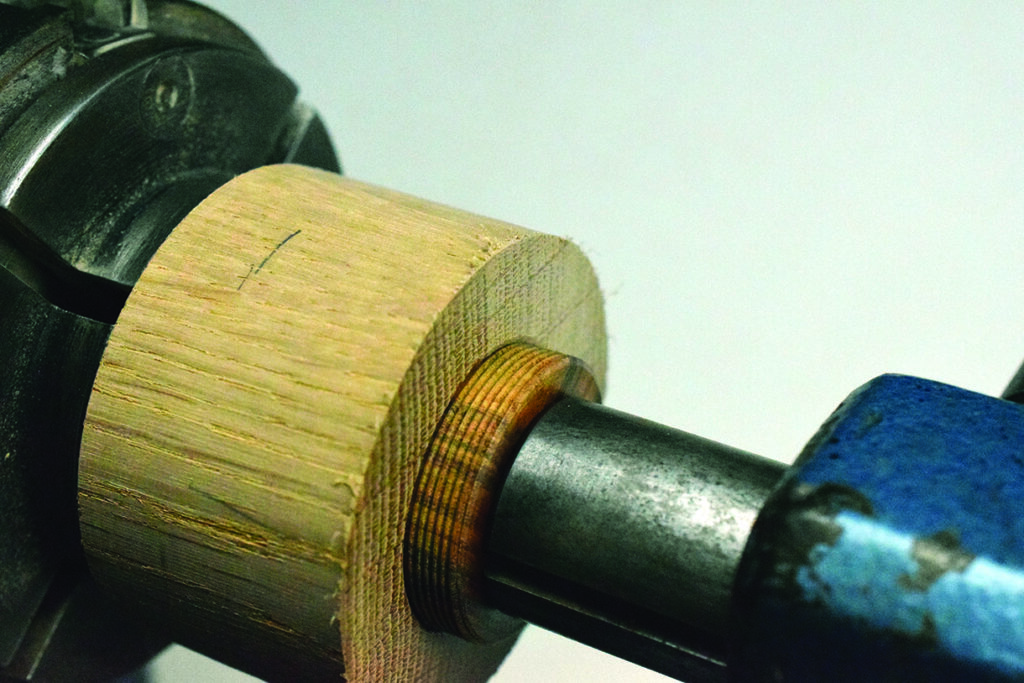 Wood turning on metal lathe machine close-up.