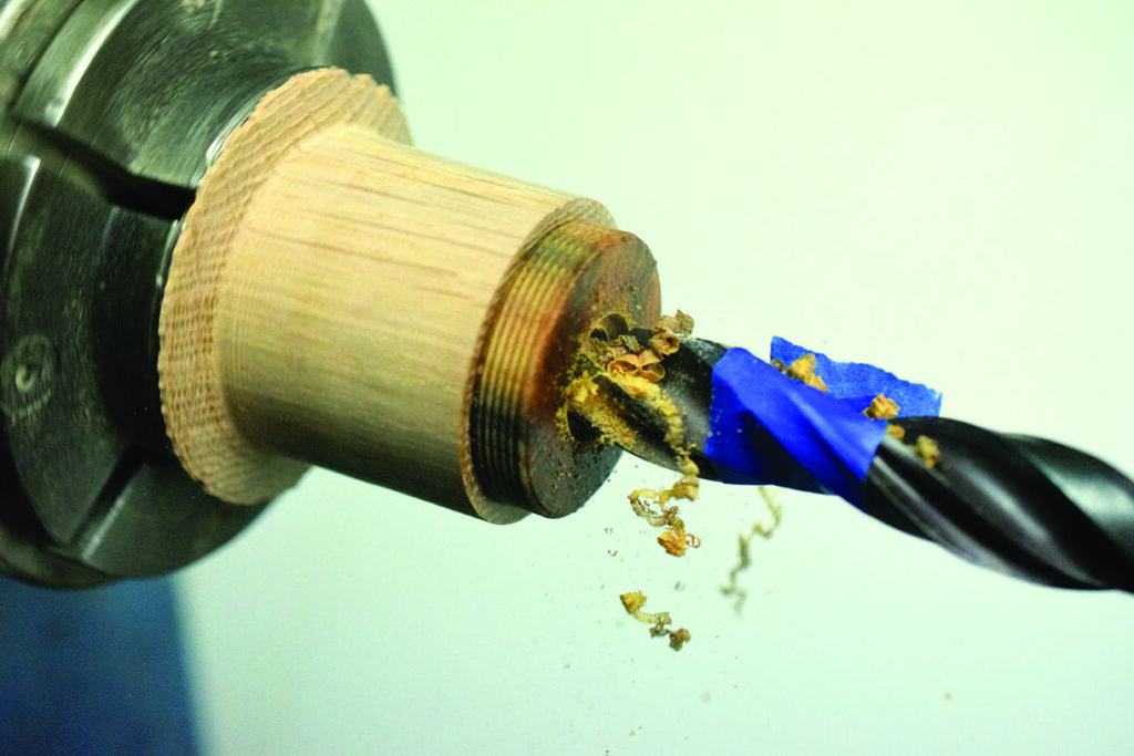 Drilling into wood with spiral drill bit.