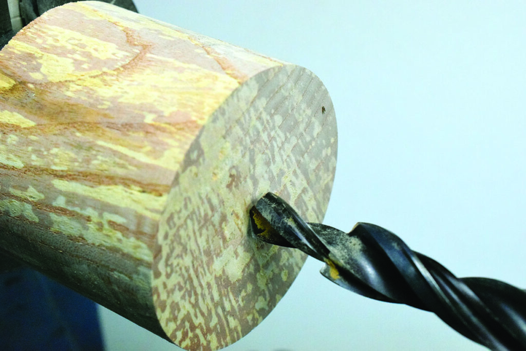 Drill bit boring into wooden cylinder close-up