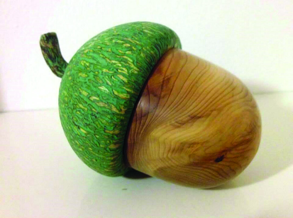 Carved wooden acorn with green textured cap.