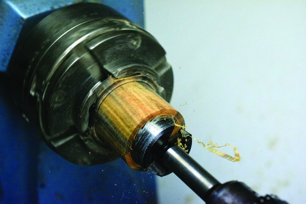Woodturning on lathe with metal tool.