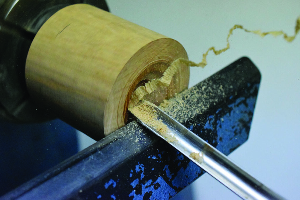 Woodturning process with lathe and chisel.